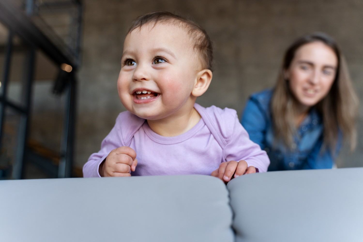 Baby smiling while his mother watches him