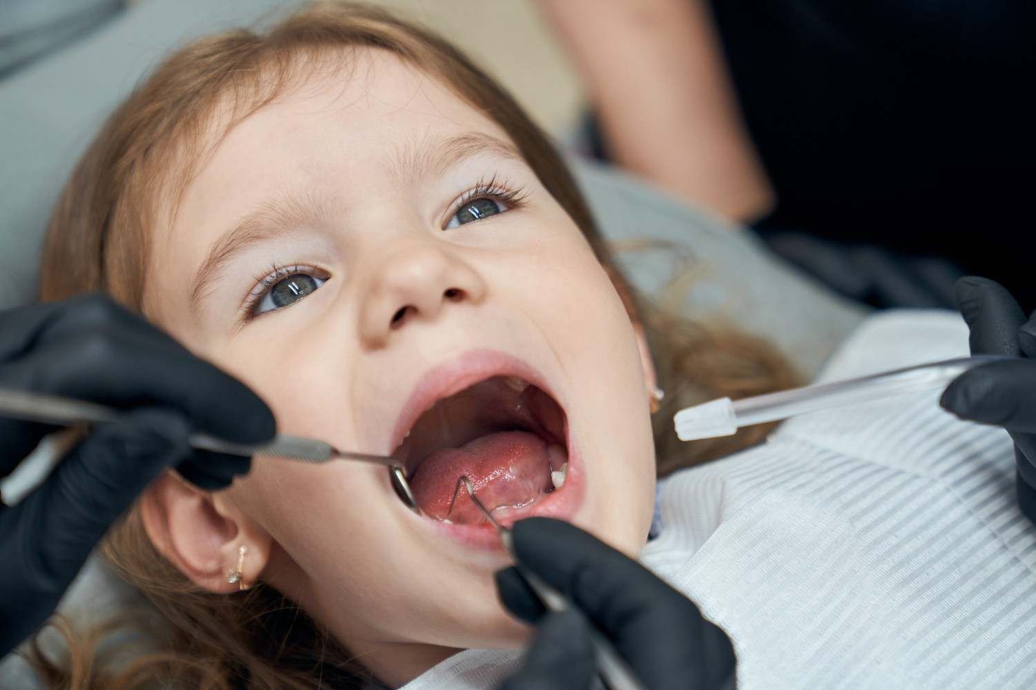 Dentist examining the condition of a little patient's teeth, Sunshine KiDDS Dentistry