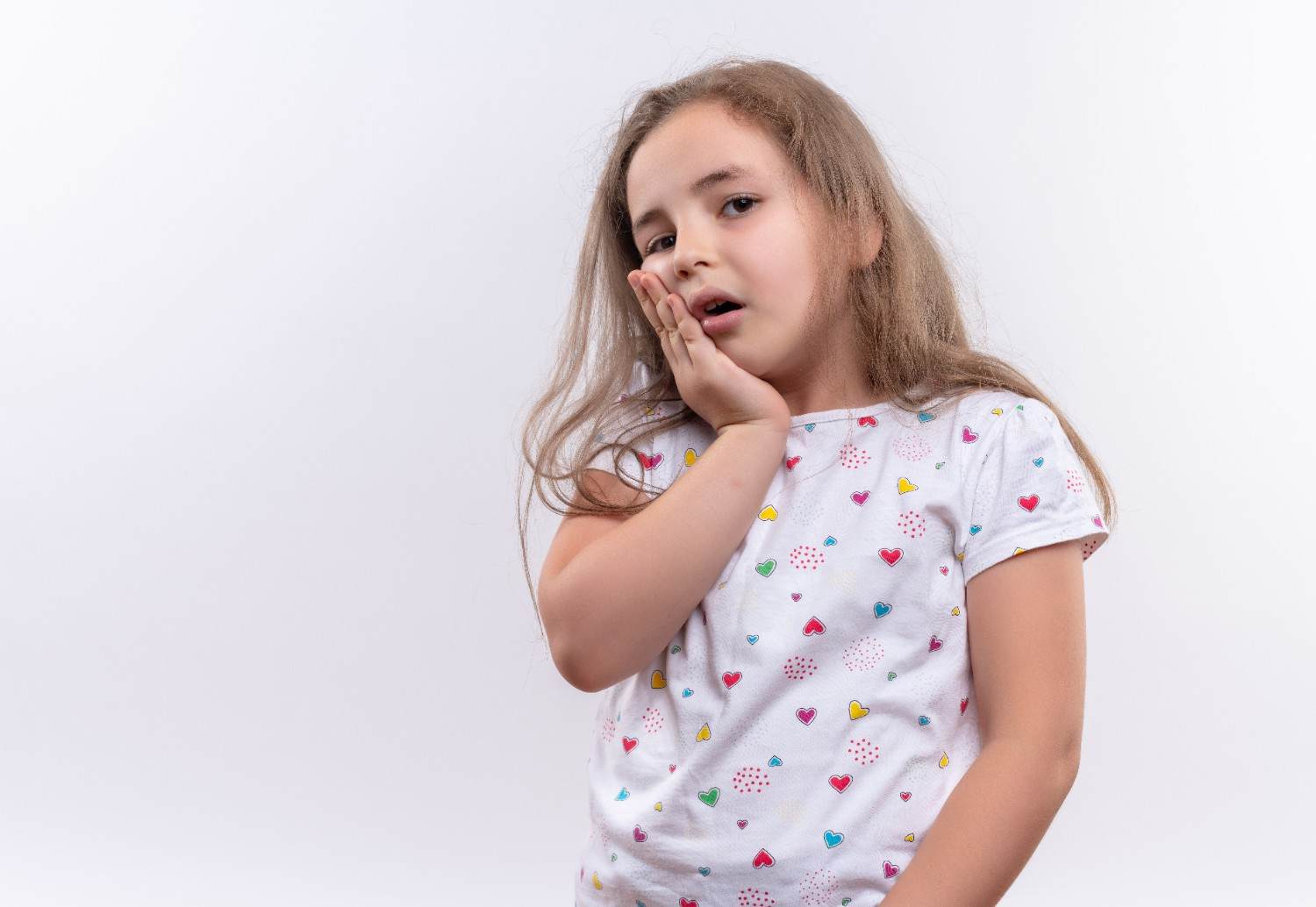 Little girl holding her cheek due to tooth pain